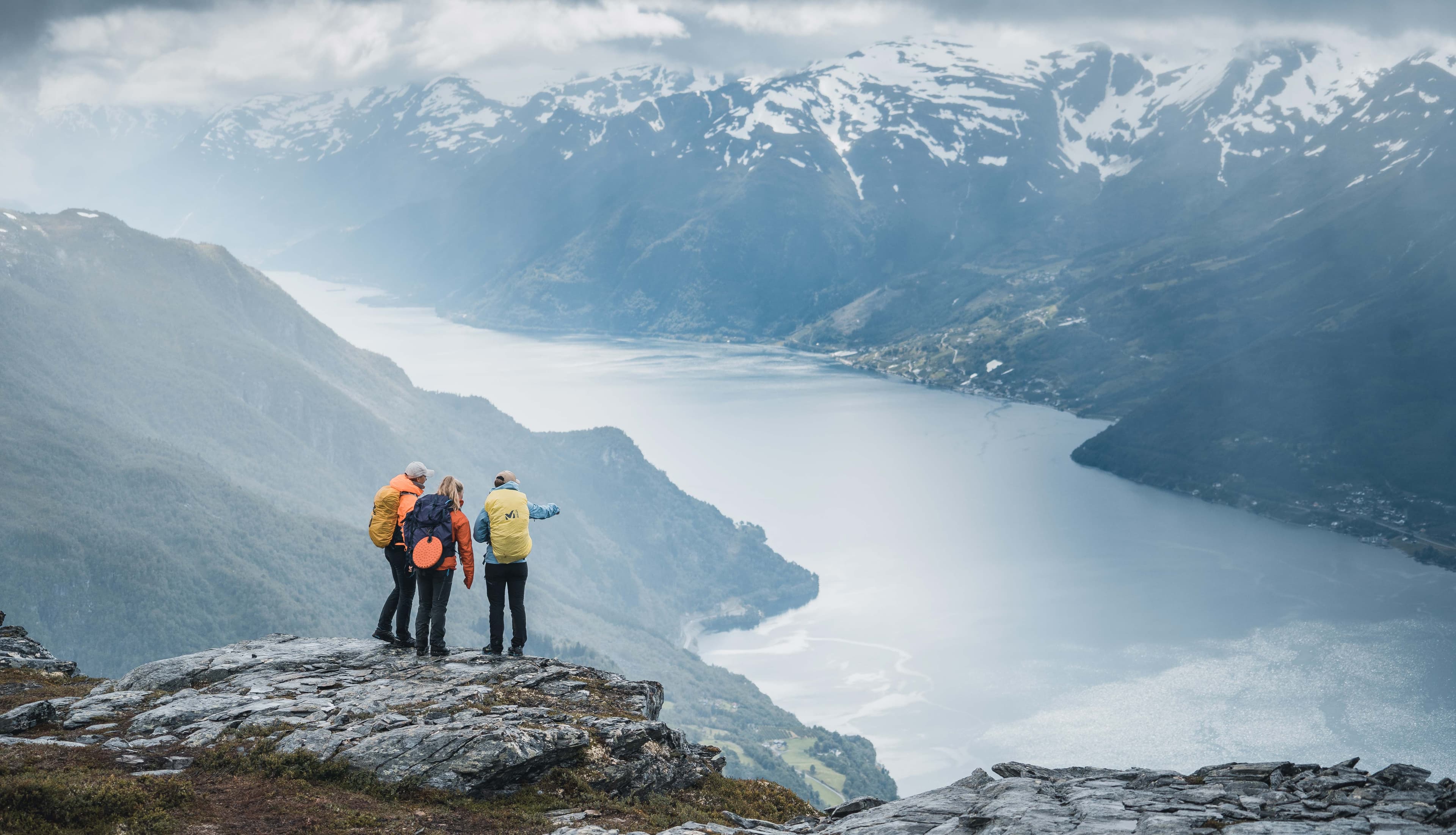 Tre turgåarar på toppen av Dronningstien med storslått utsikt over Sørfjorden og Folgefonna i bakgrunnen.