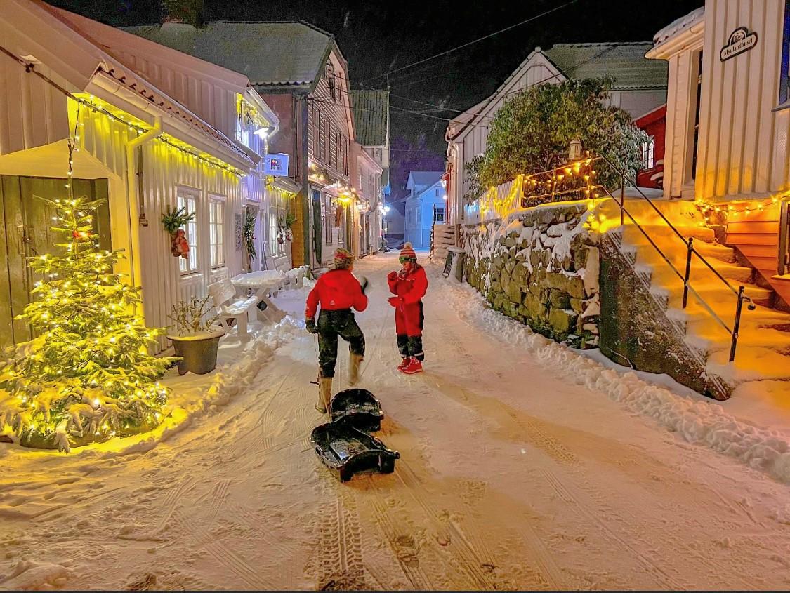 Sogndalstrand kulturhotell i vinteren. To personer med sleder.