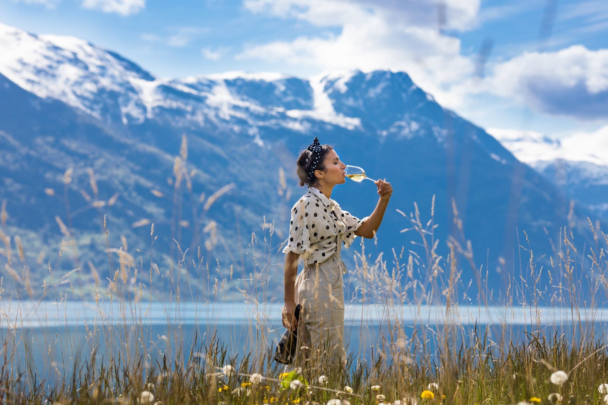 Kvinne som nyt eit glas Edel Sider i vakkert fjellandskap ved Hardangerfjorden.