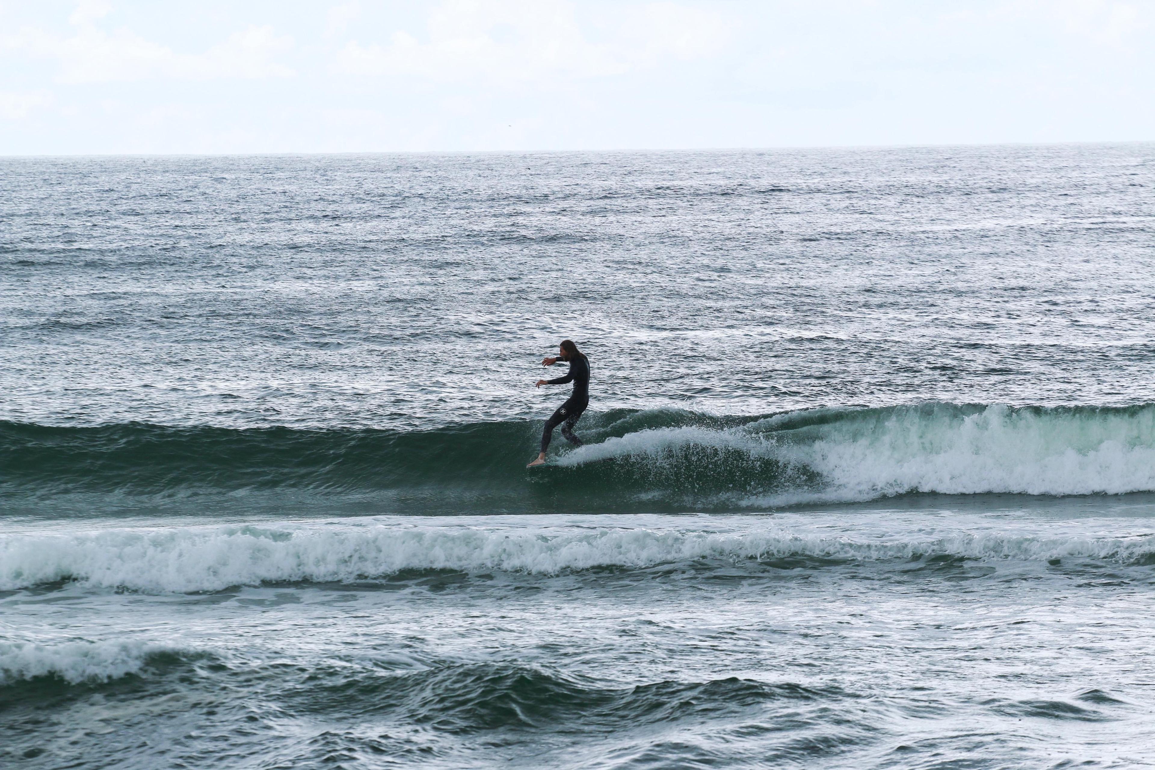 Surfer som står på brettet i bølgene.