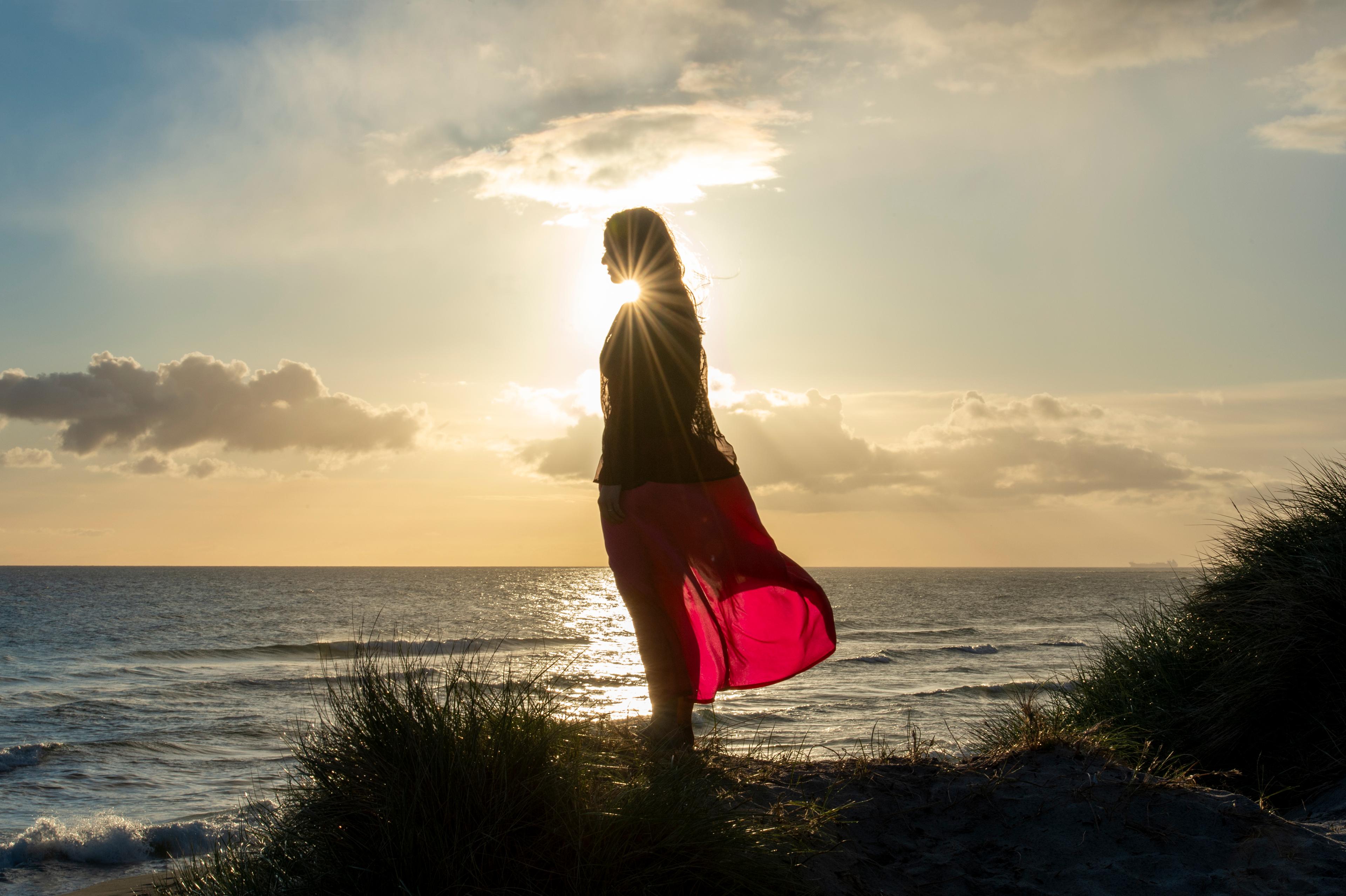 lady looking out to sea from orre beach in sunset