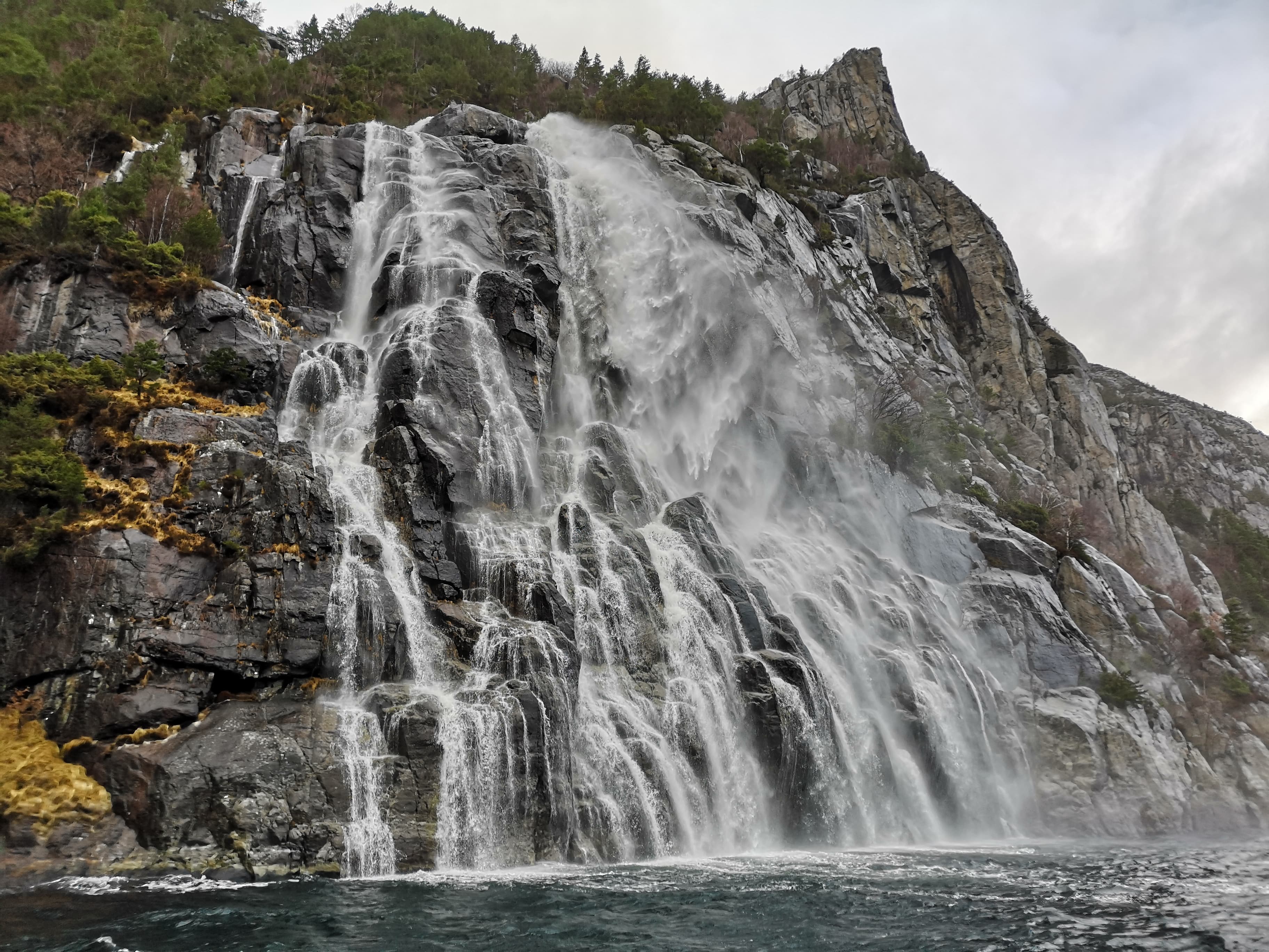 Foss som strømmer ned fjellside like ut i en fjord