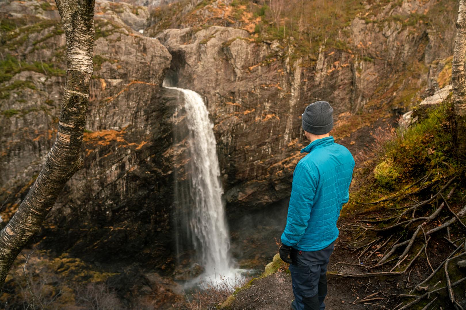 Man watching a waterfall in scenic surroundings in Norway