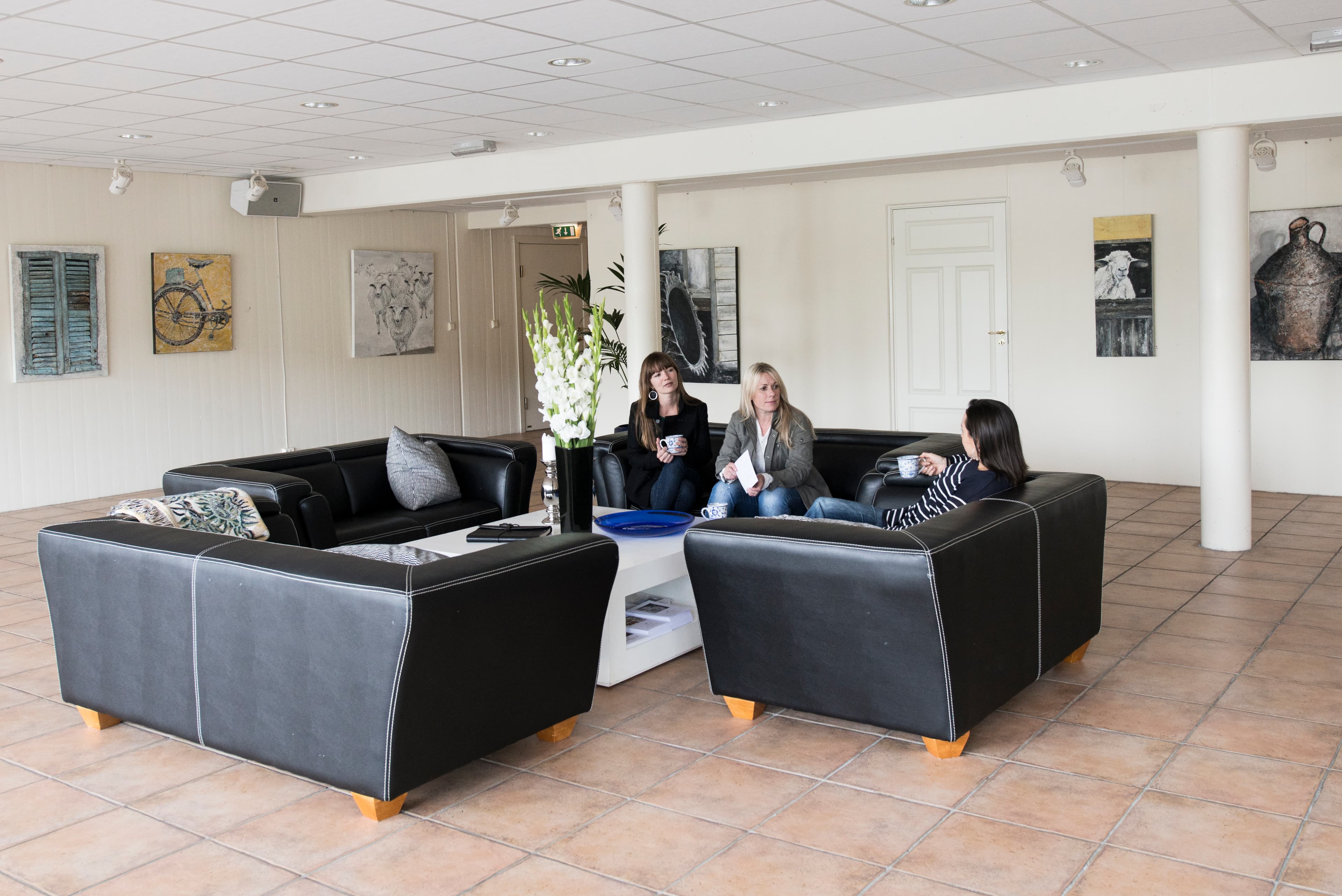 Tre personer som sitter i en sittegruppe i galleri Perlemorstrand.