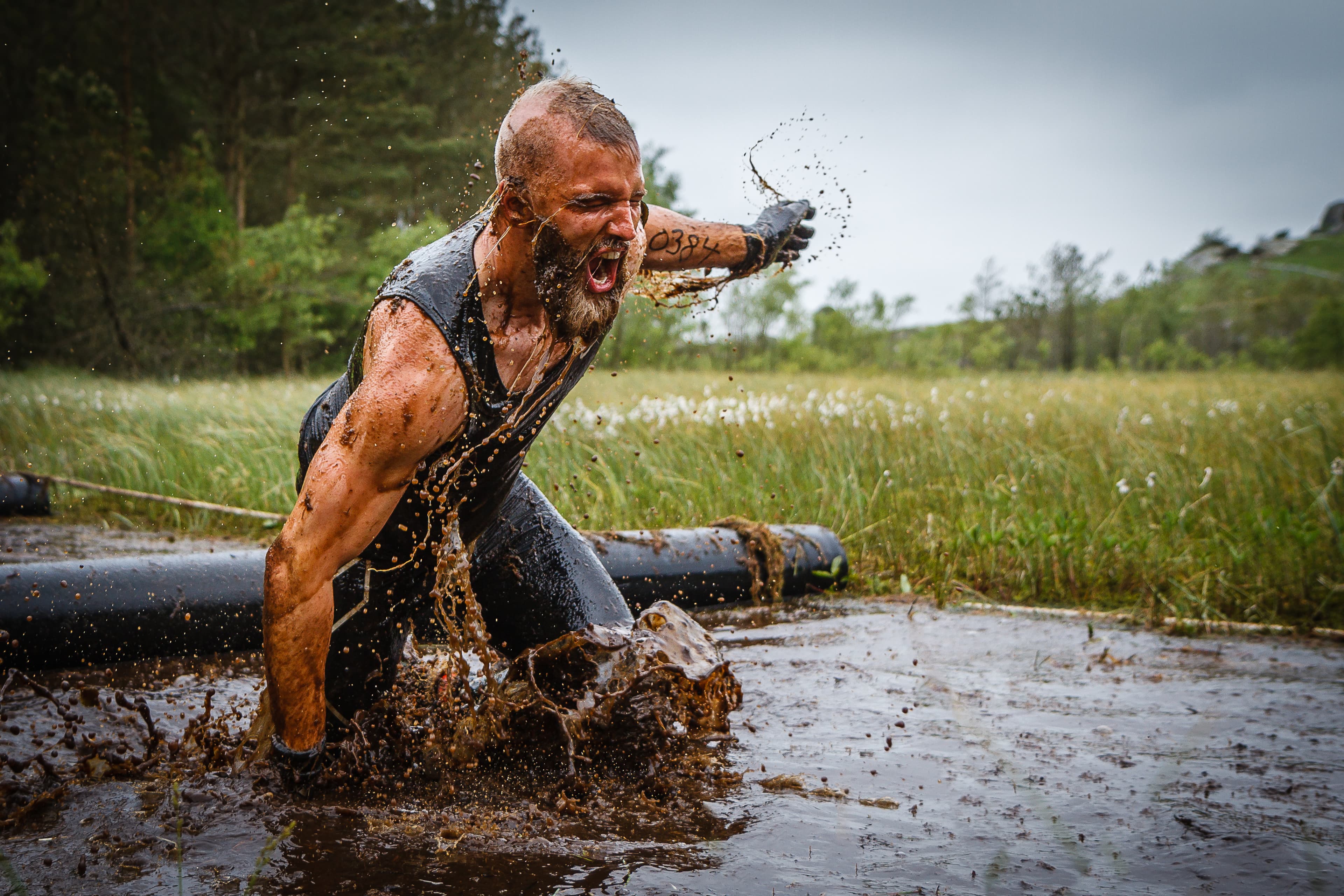 Mann som kjemper seg gjennom et gjørmete vann i forbindelse med en styrkeprøve.