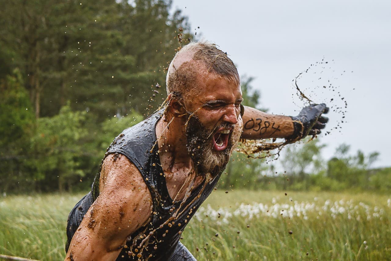 Mann kjemper seg gjennom gjørme i ekstremhinderløype i Trolljegerløpet
