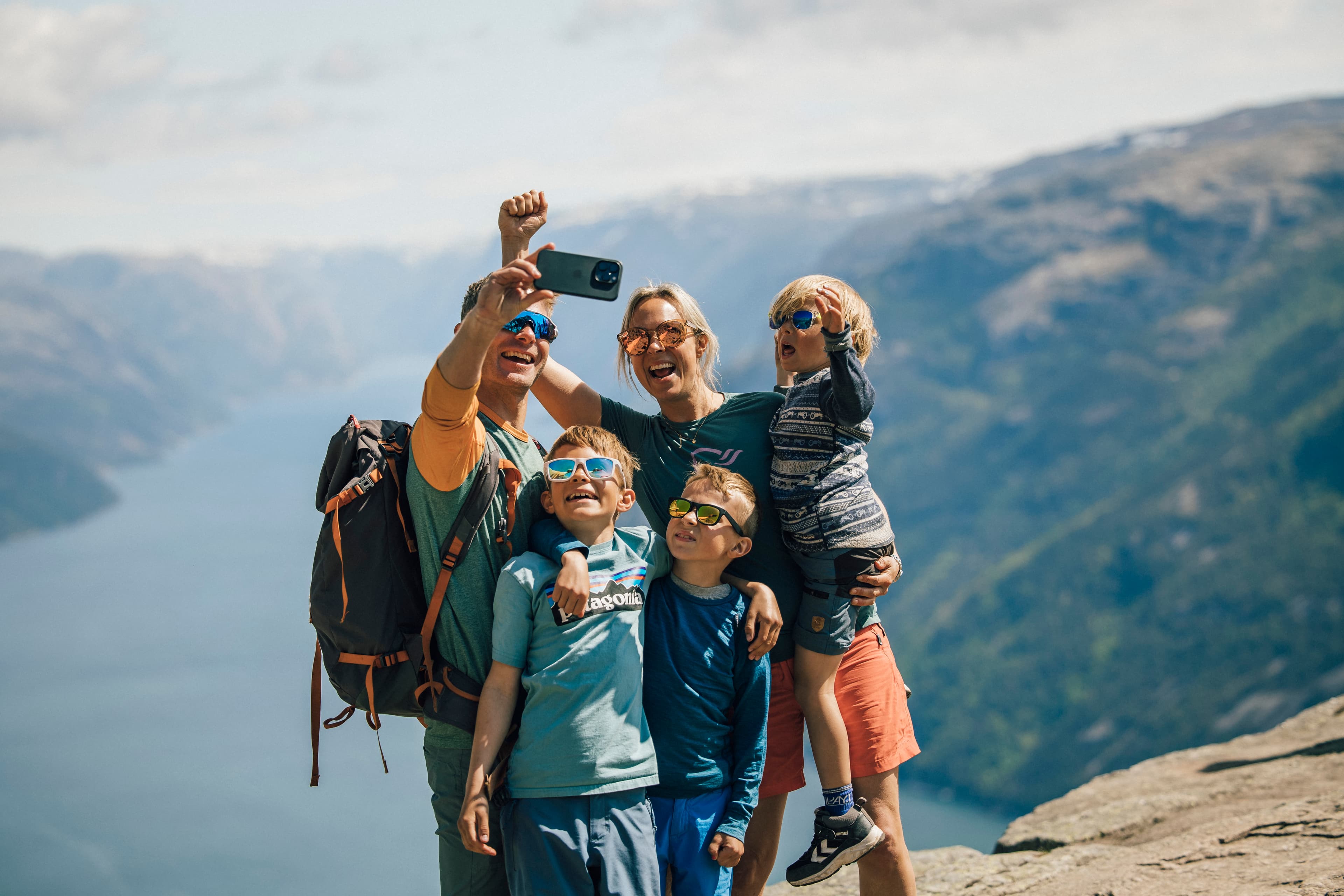 A family taking selfie on top of mountain plateau Preikestolen with the fjord as backdrop