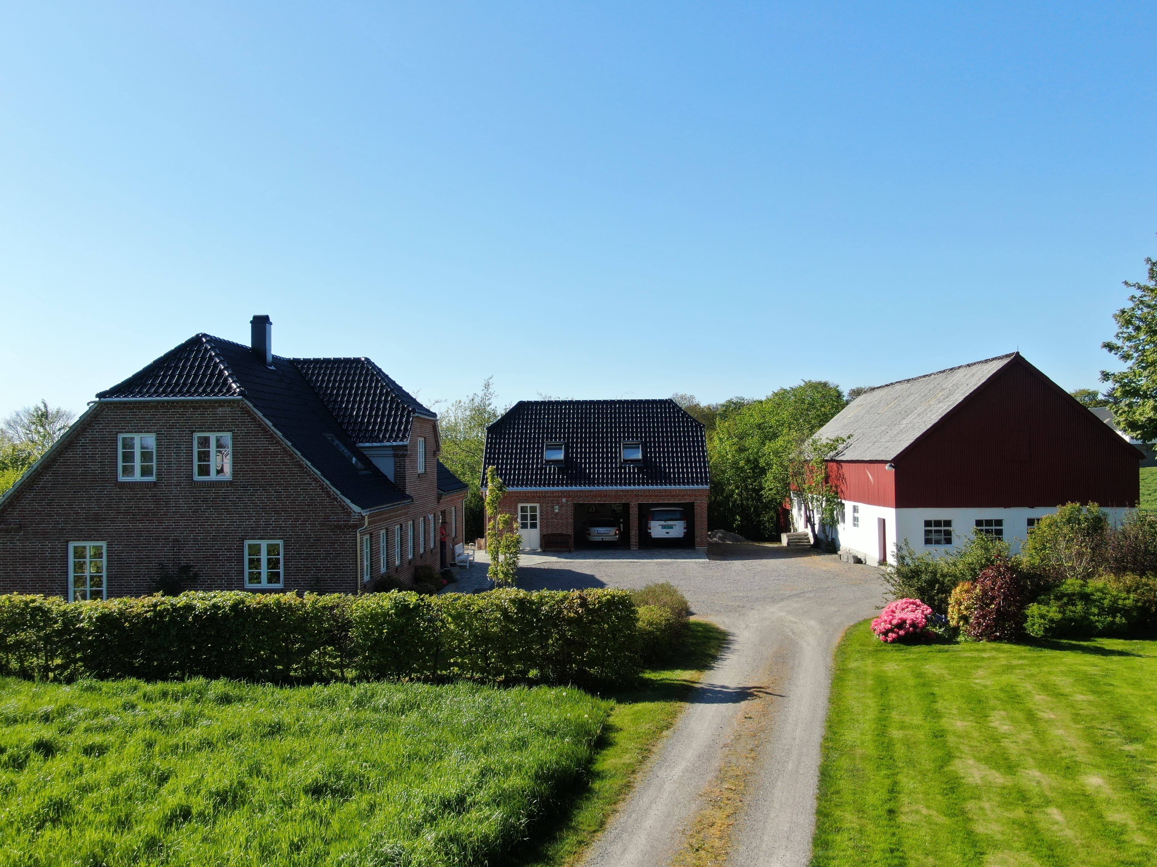 A small farm with accommodation, Vigrestad Bed & Eggs. Three, red buildings in front of green fields.