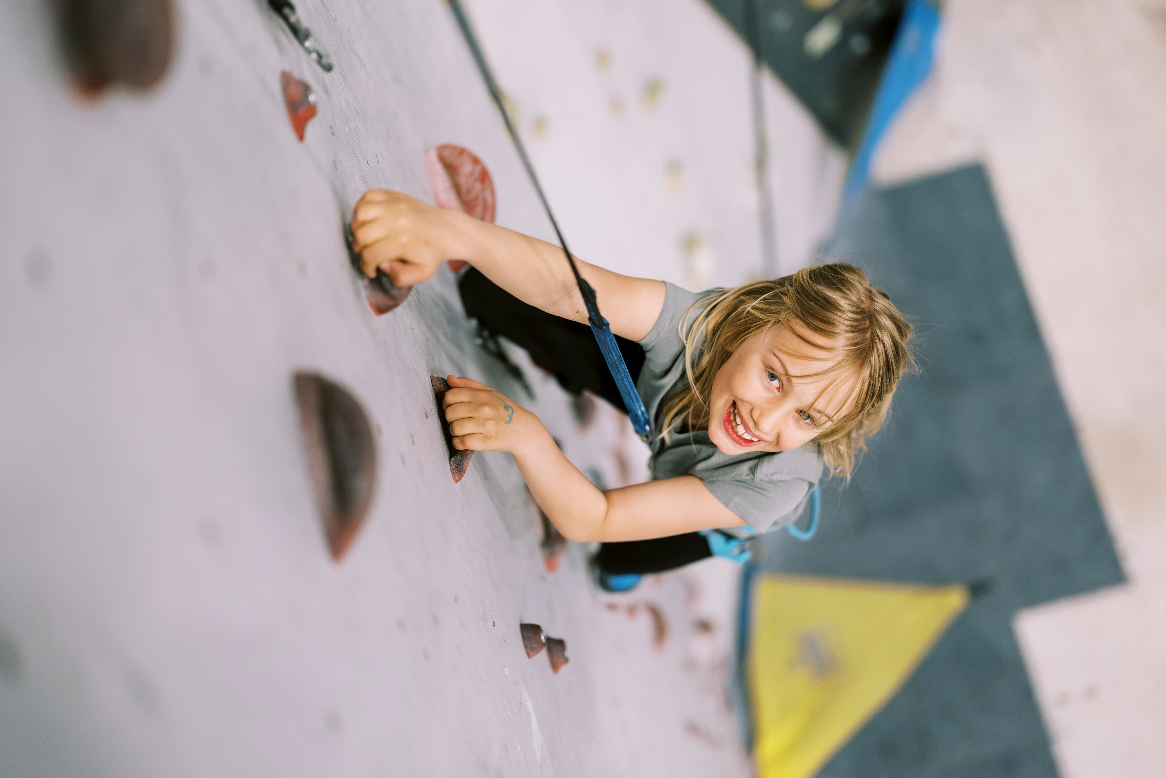girl climbing up a climbing wall at Playground